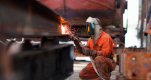 Welder welding girder in shipyard workshop